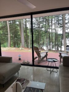 Ferienhaus-Terrasse mit Blick auf den See und umgeben von Bäumen.